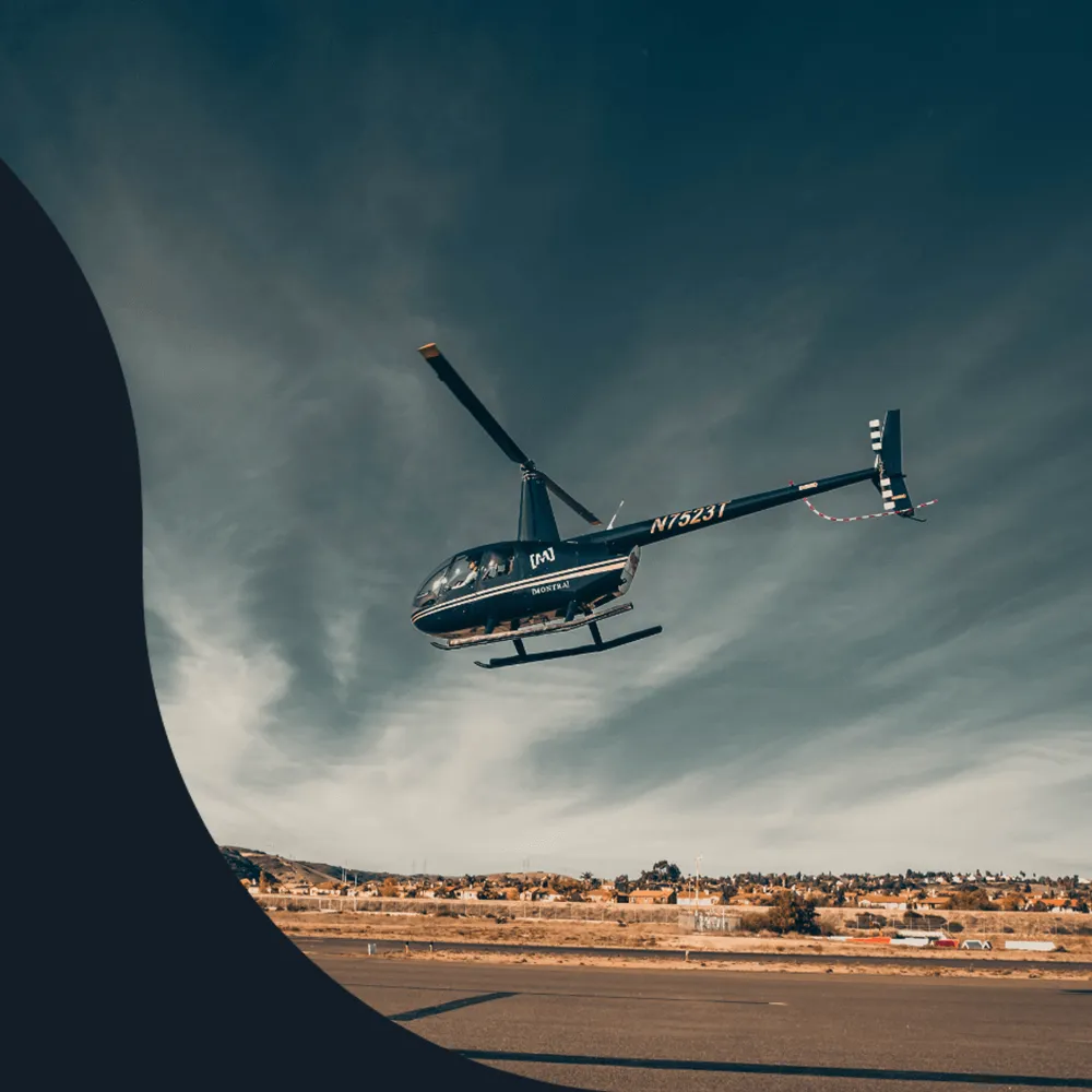 Helicopter lifting off from an airfield under a streaked blue sky