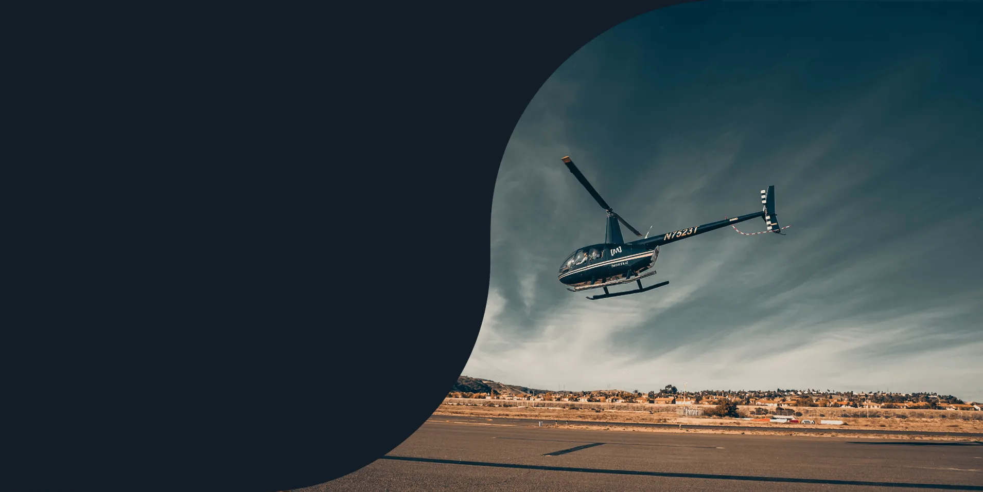 Helicopter lifting off from an airfield under a streaked blue sky